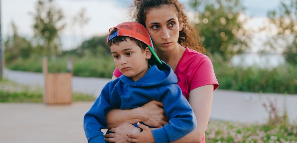 امرأة تعانق طفلها بحزن