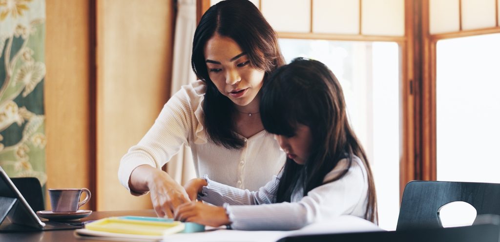 امرأة تساعد طفلتها في حلّ واجباتها المدرسية