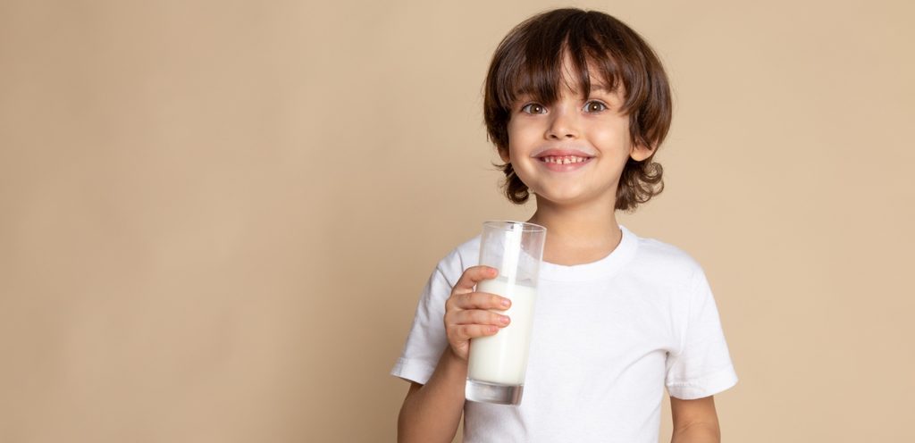 طفل سعيد يمسك كوبًا من الحليب