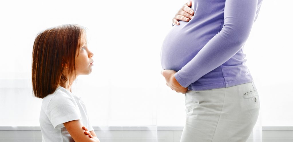 طفلة  غاضبة تنظر إلى والدتها الحامل