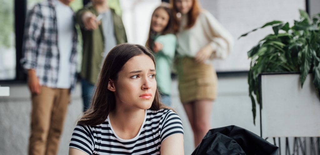 شابّة حزينة وخلفها أشخاص يضحكون