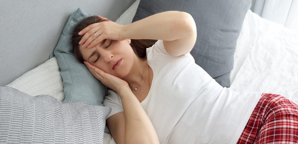 امرأة تعاني من مشاكل في النوم مستلقية على السرير
