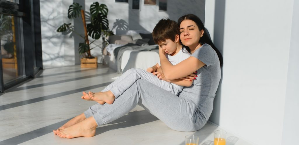 امرأة تجلس على الأرض تعانق طفلها