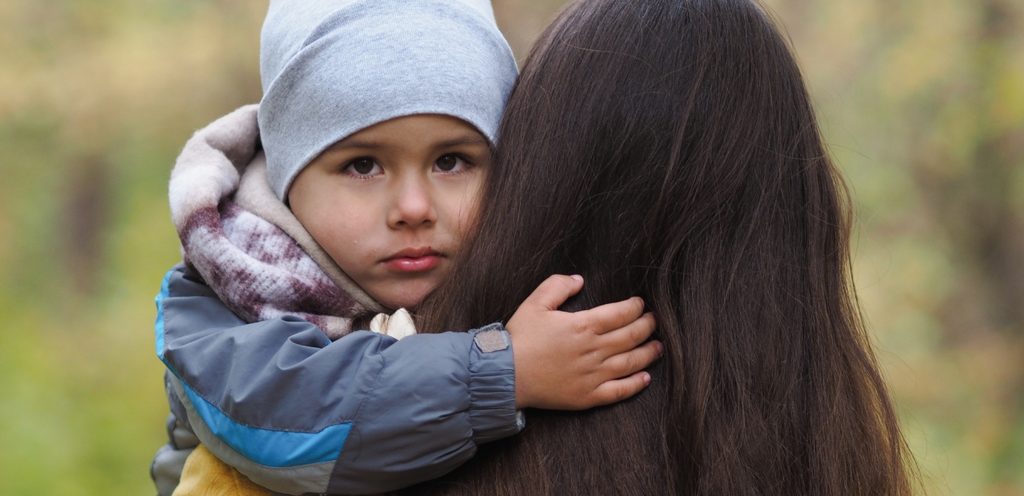 طفل حزين يعانق والدته
