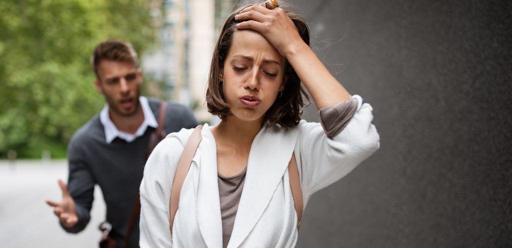 امرأة حزينة تمشي وزوجها خلفها يتكلّم بغضب