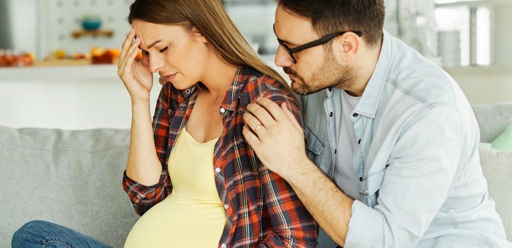 امرأة حامل حزينة وزوجها يواسيها