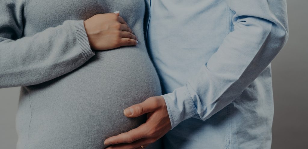 امرأة حامل وزوجها يضع يديه على بطنها