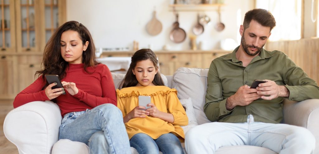 أم وأب وطفلة يستخدمون الهواتف