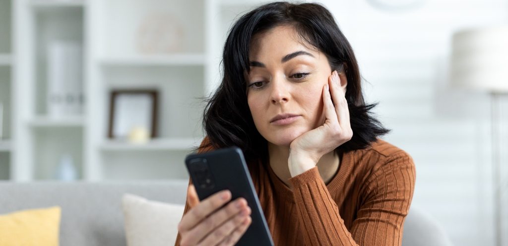 امرأة حزينة تنظر إلى هاتفها