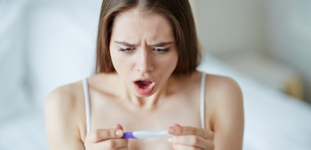 امرأة متفاجئة تمسك اختبار حمل