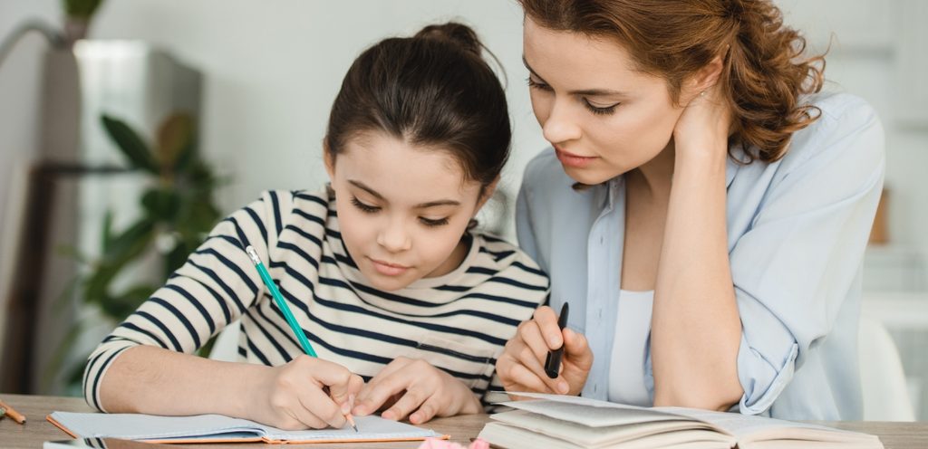 امرأة تساعد طفلتها في حلّ واجباتها المدرسية