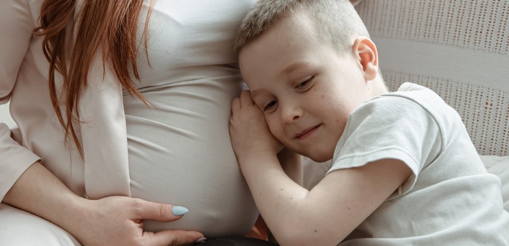 طفل سعيد يضع أذنه على بطن والدته الحامل