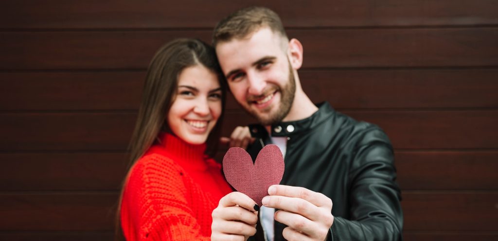 زوجان سعيدان يمسكان قلب أحمر