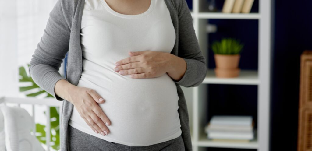 امرأة حامل تضع يديها على بطنها