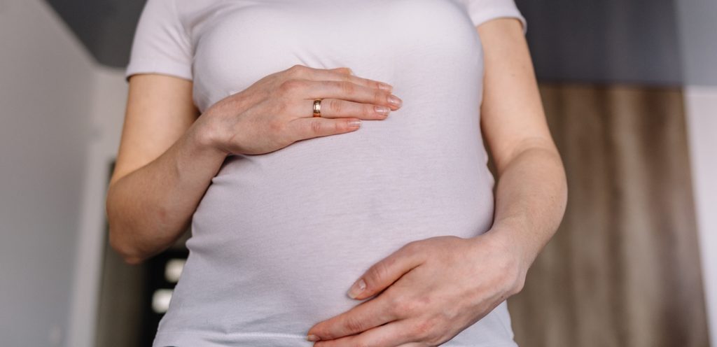 امرأة حامل تضع يديها على بطنها