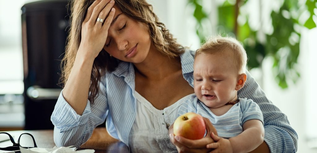 أم متعبة تحمل طفلها