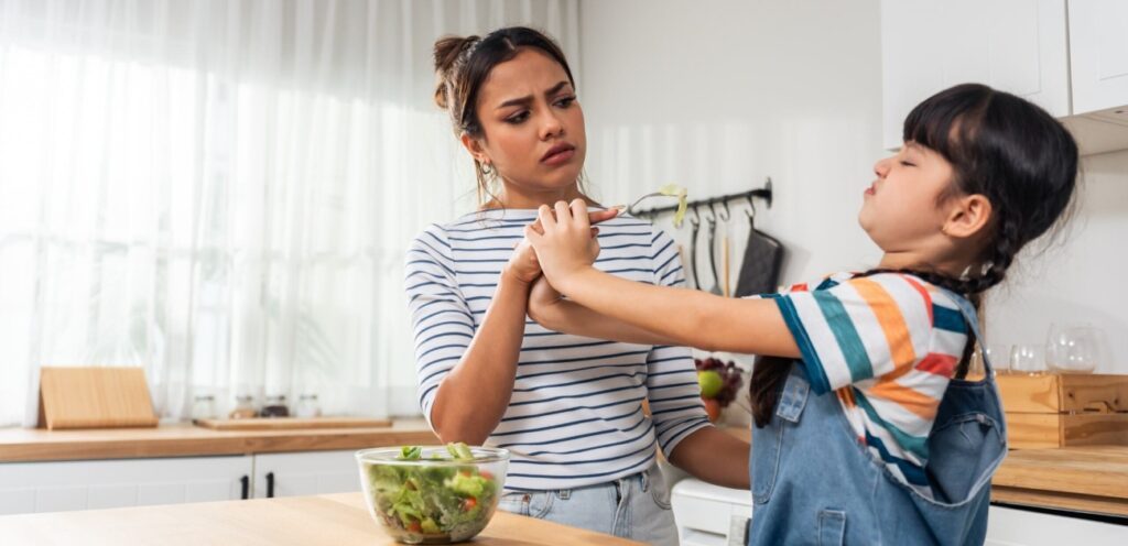 امرأة تحاول إطعام طفلتها وهي ترفض