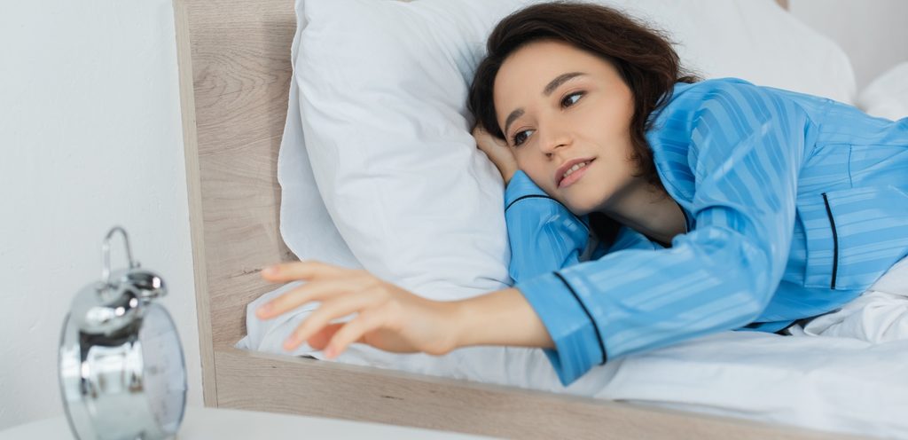 امرأة في السرير تطفأ المنبه