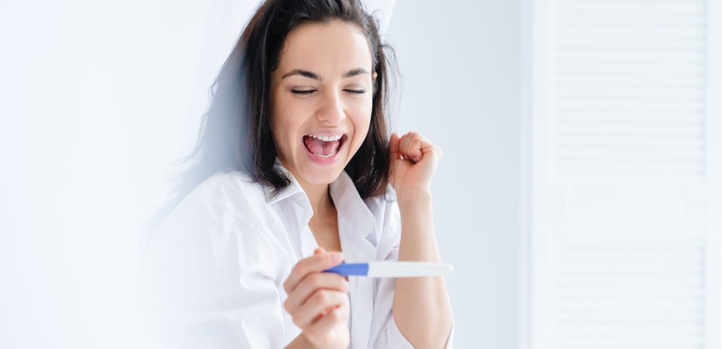 امرأة سعيدة تمسك اختبار حمل