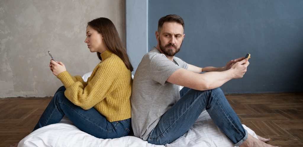 امرأة ورجل يجلسان متعاكسين ويمسك كلّ منهما جوّاله