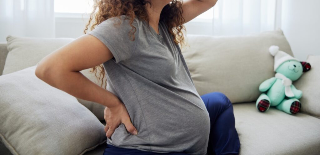 امرأة حامل تضع يديها على ظهرها