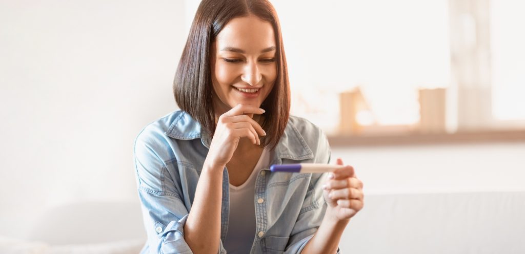 امرأة سعيدة تمسك اختبار حمل