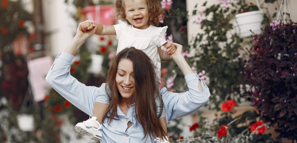 أم تحمل طفلتها على كتفيها