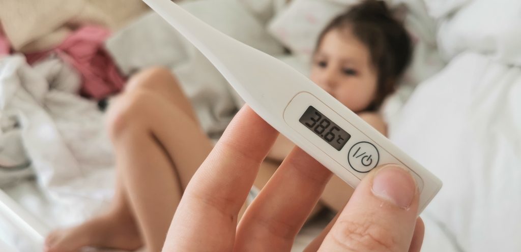 امرأة تمسك ميزان حرارة وطفلتها أمامها