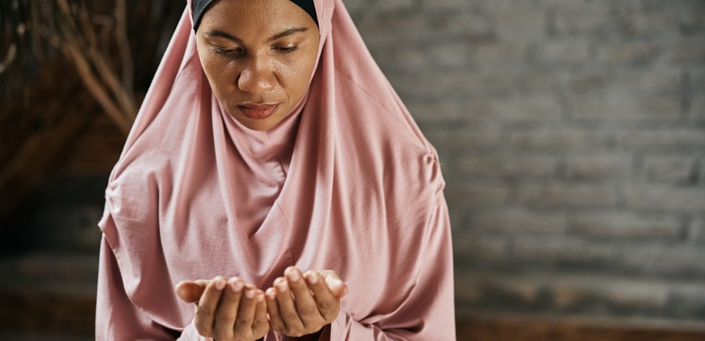 امرأة ترفع يديها للدعاء