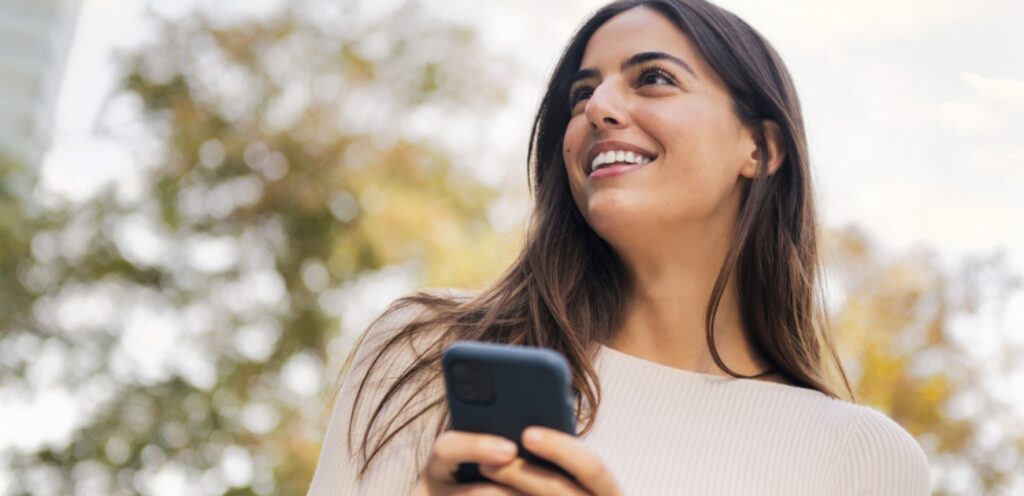 امرأة سعيدة تمسك جوّالها