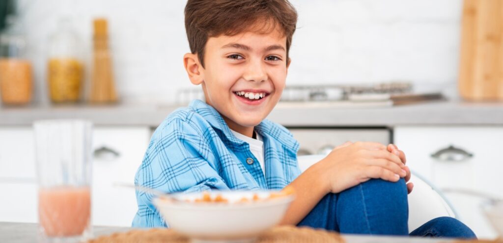 طفل سعيد يجلس على مائدة الطعام