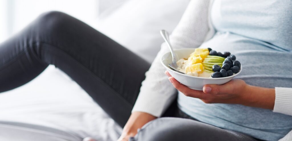 امرأة حامل تمسك طبقًا من الفواكه