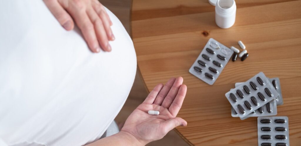 امرأة حامل تمسك حبوب دواء