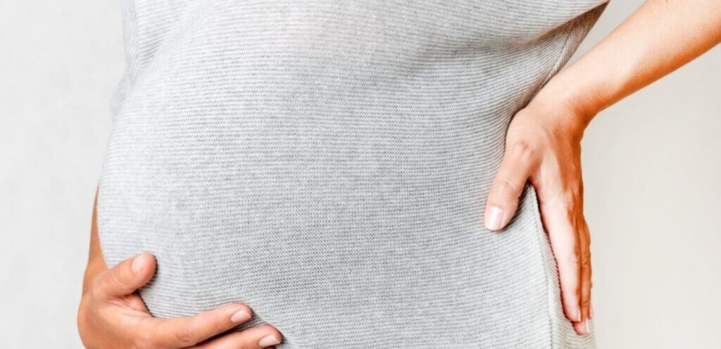 امرأة حامل تضع يديها على بطنها