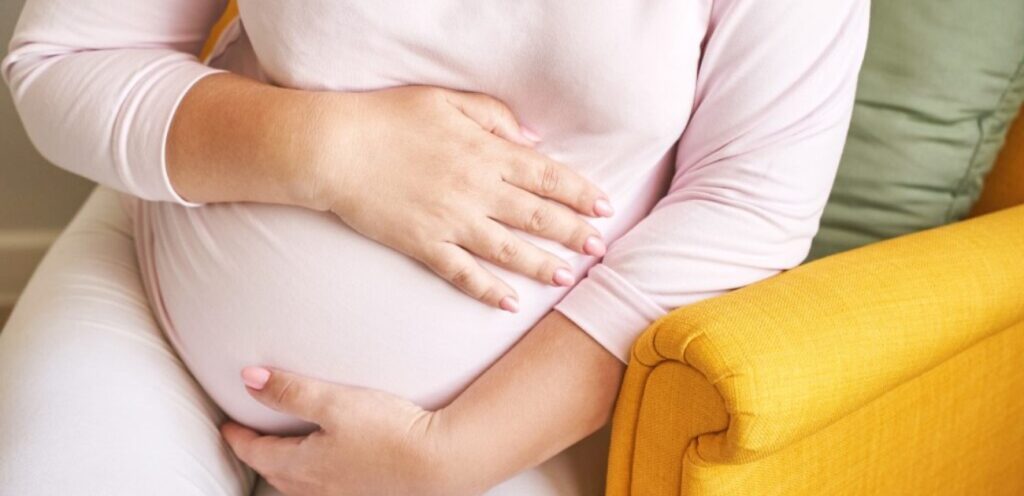 امرأة حامل تضع يديها على بطنها