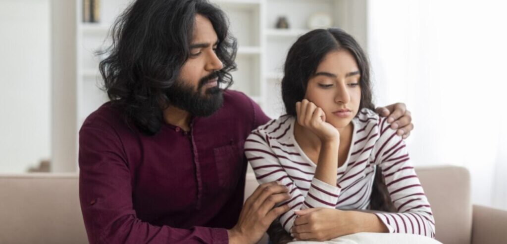 امرأة حزينة ورجل يحاول مواساتها