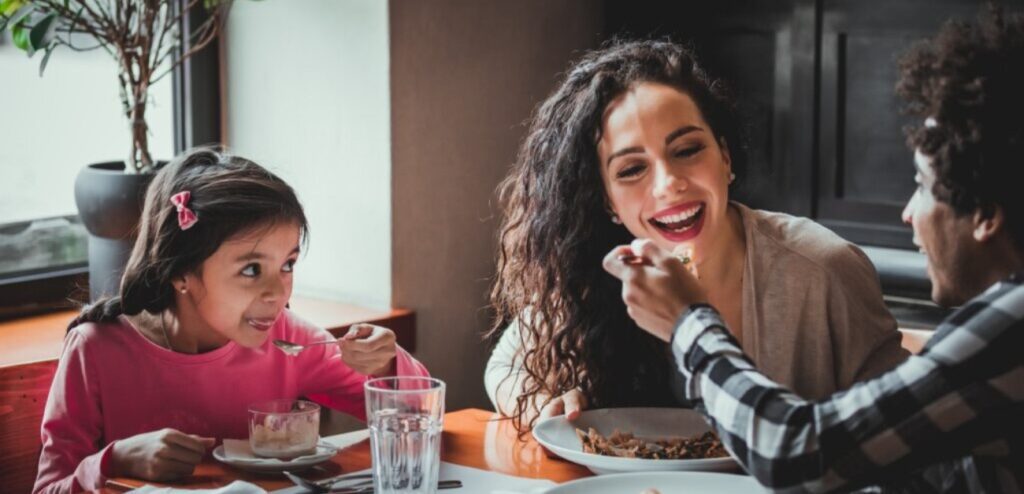 امرأة وزوجها وطفلتها يتناولون الطعام