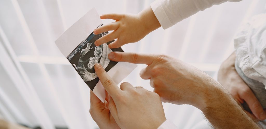 أم وأب وطفل يمسكون صورة سونار رحم