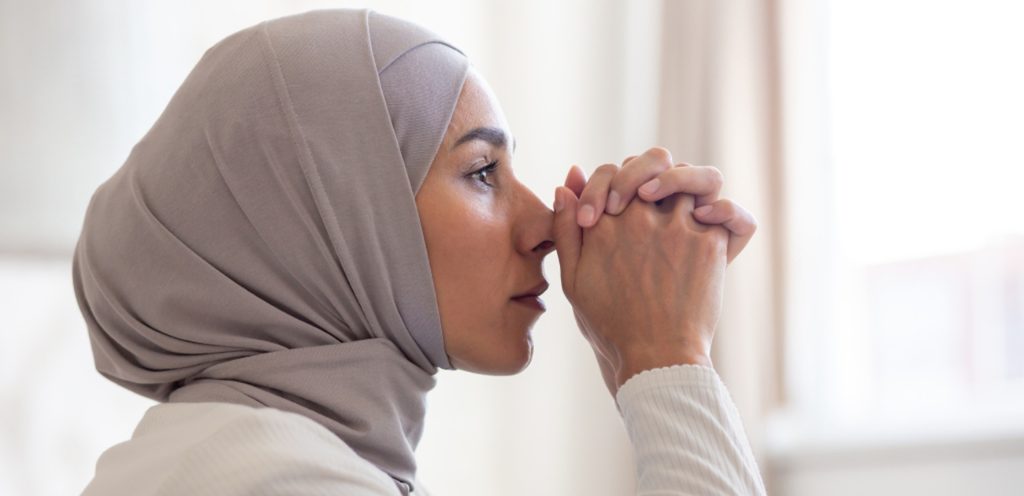 امرأة ترفع يديها للدعاء