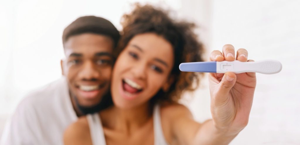 امرأة ورجل سعيدان يمسكان اختبار حمل