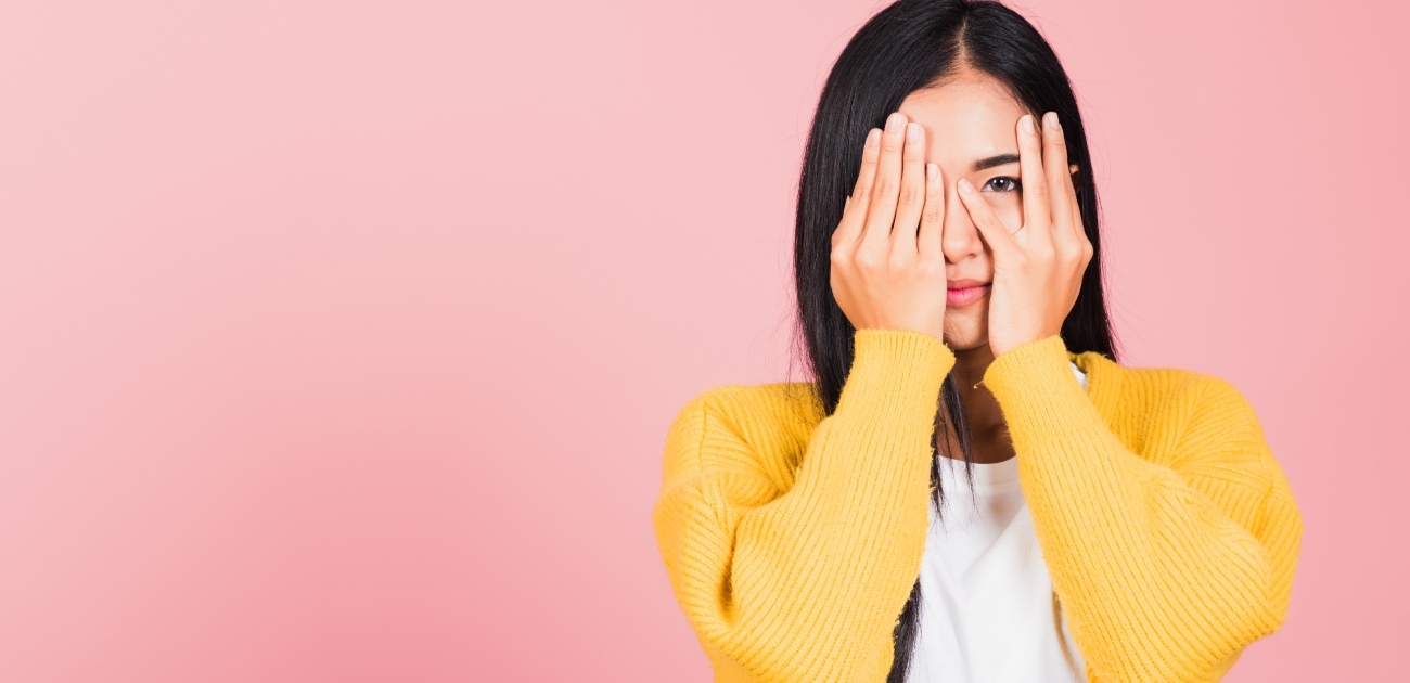 امرأة تُظهر عينها من وراء يدها
