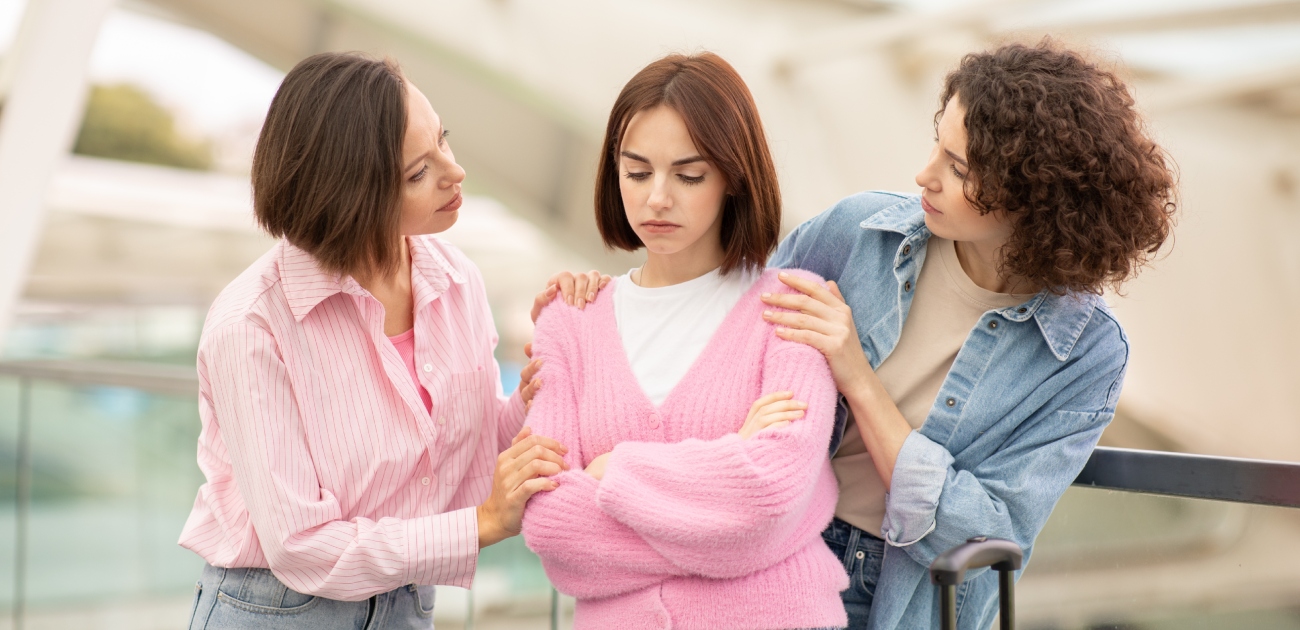 شابّة حزينة وشابّتان تحاولان مواساتها
